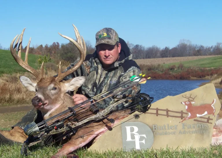 A man kneeling down next to a dead deer.